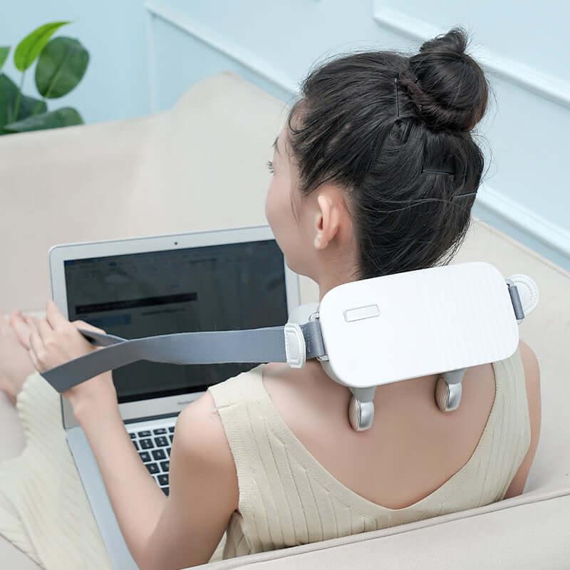 Woman using neck and shoulder massager while working on laptop, ideal for best massage chair in UAE, Dubai. كرسي مساج كرسي استرخاء كرسي مساج كهربائي
