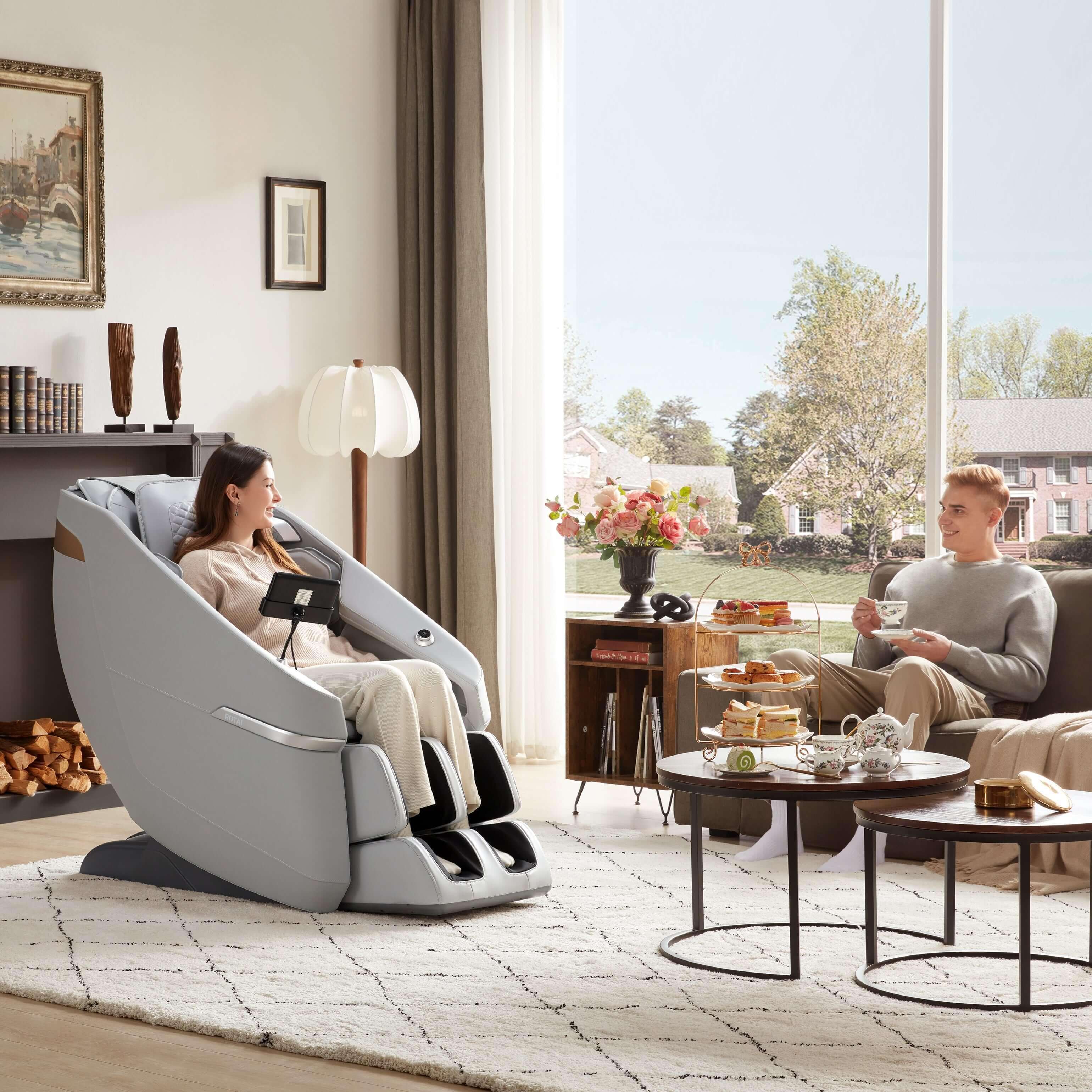 Woman using Ekanite Massage Chair and Sofa in living room with tablet control while man relaxes, showcasing best massage chair in UAE. best massage chair uae, massage chair Dubai, massage chair uae, massage chair Saudi Arabia, كرسي التدليك, Best massage c